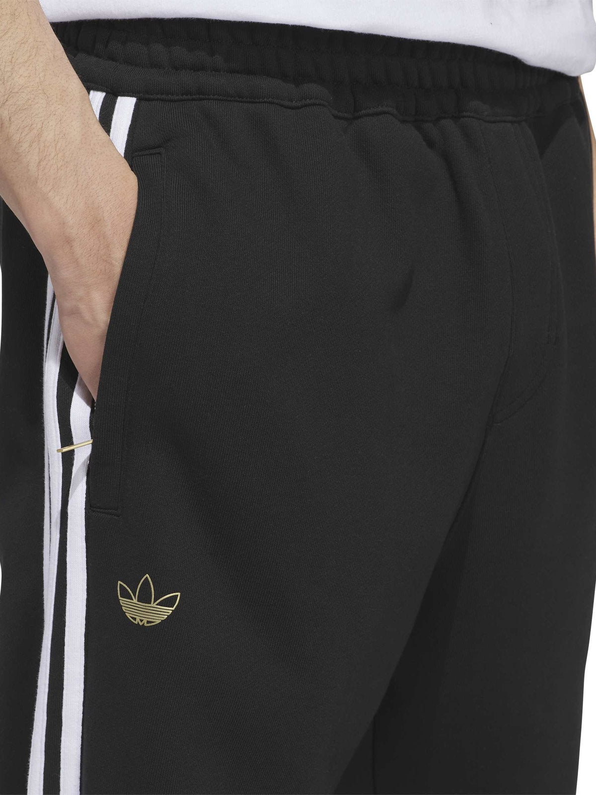 Pantalons Adidas Tysh Trck Pant Black/White, gros plan sur la poche, les trois bandes blanches et le logo trèfle doré