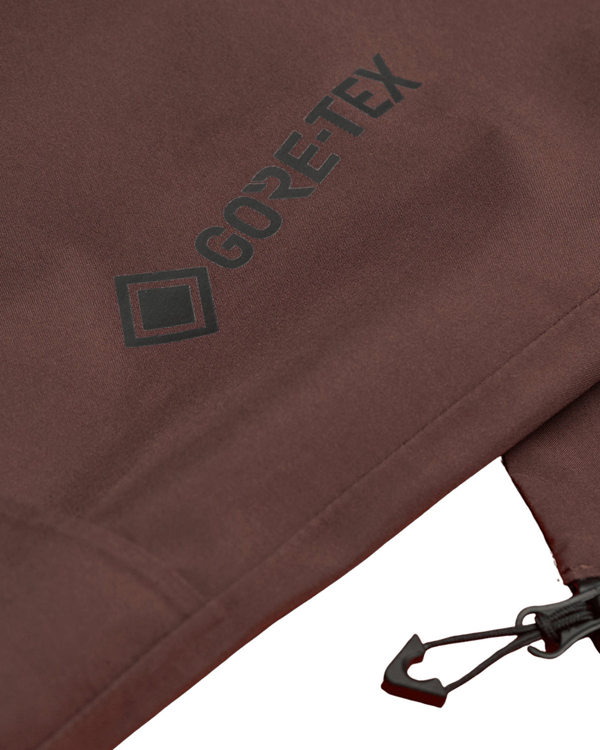 Vestes Element Mxe Shell Gtx J (N353) Truffle Mxe, gros plan sur le logo « GORE-TEX » imprimé en noir sur le tissu marron d'une veste technique.