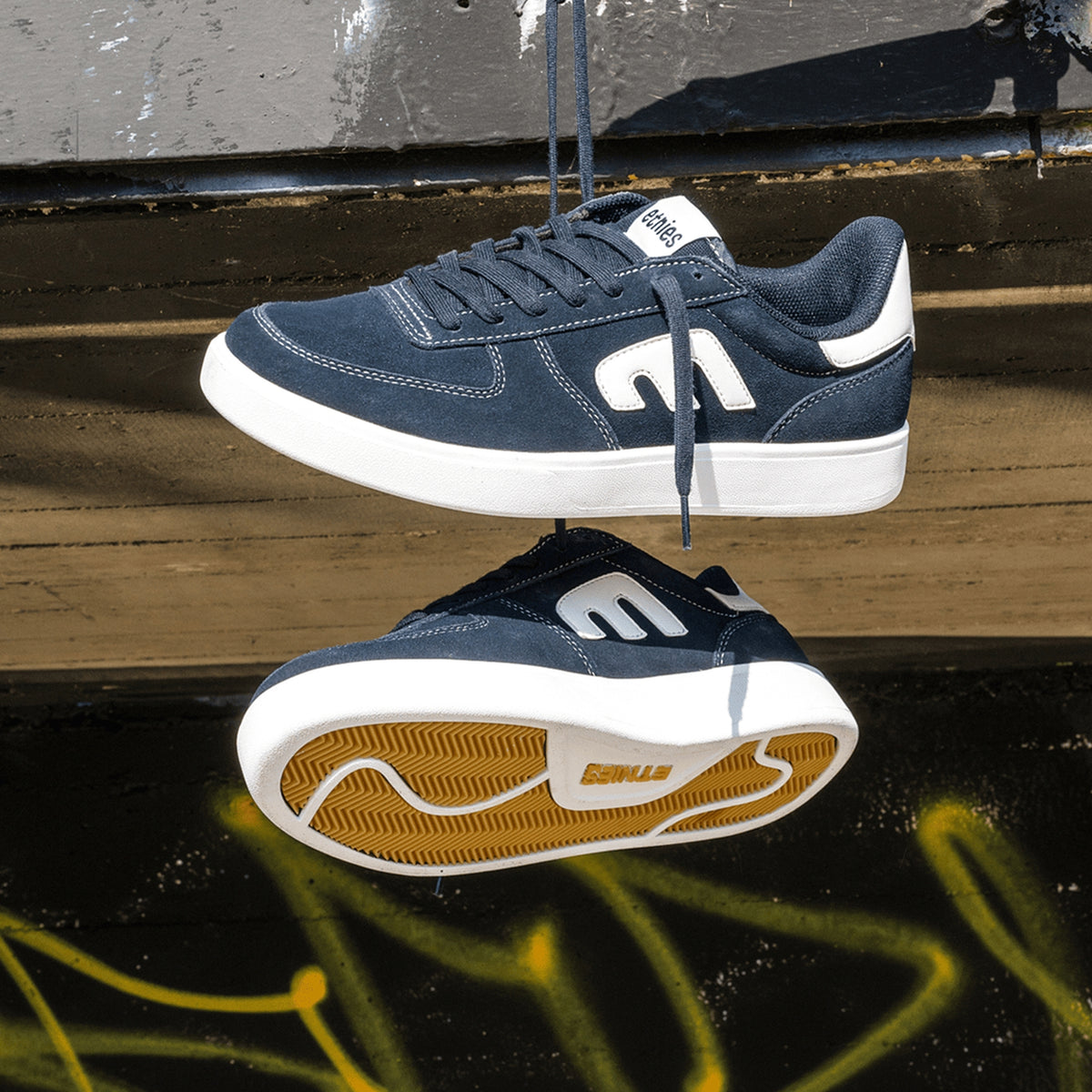 Chaussures de skateboard Etnies Etnies Emerson X Fos Navy White Navy White, vue de la paire de chaussure suspendues par leurs lacets en extérieur